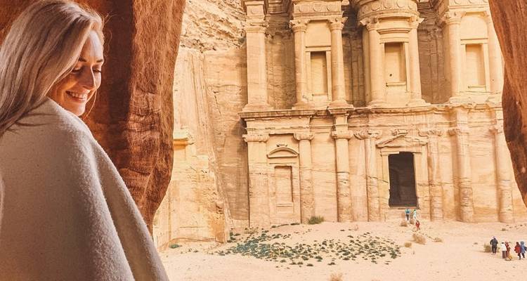 Person, die auf die antike Fassade von Petra blickt.