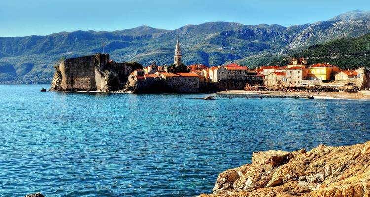 Coastal town with historic buildings and a church tower by the sea.