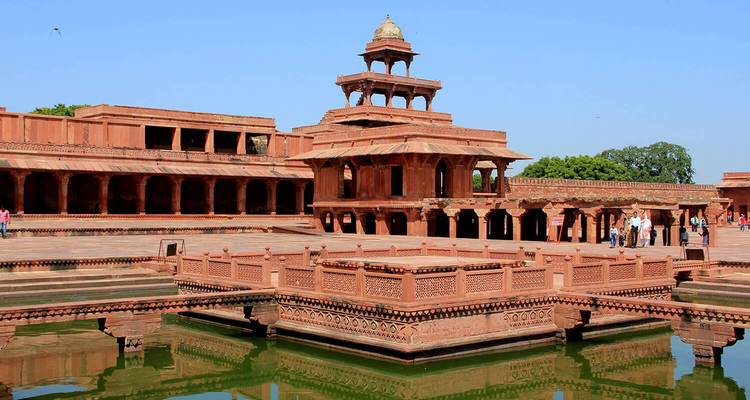 Rood zandstenen paleiscomplex met een waterlichaam ervoor.