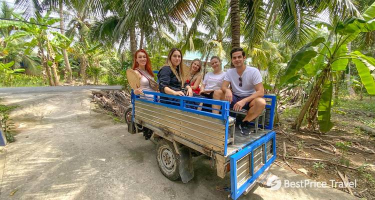 Groep mensen zittend op een kar omringd door tropische planten.