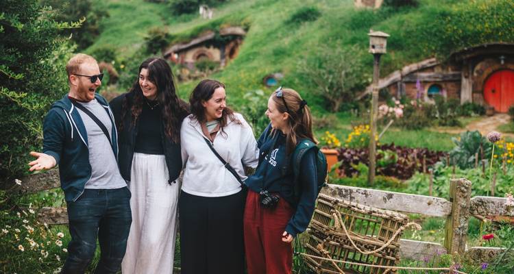 Groupe de personnes souriantes sur le plateau de Hobbiton en Nouvelle-Zélande.