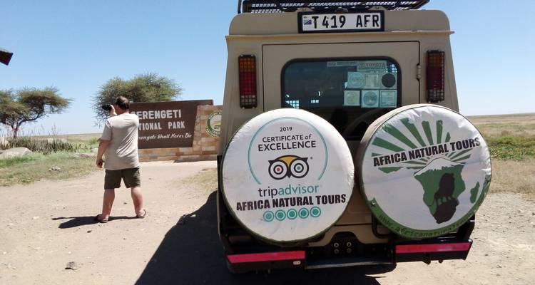 Ein Safari-Fahrzeug geparkt in der Nähe des Schilds vom Serengeti-Nationalpark.