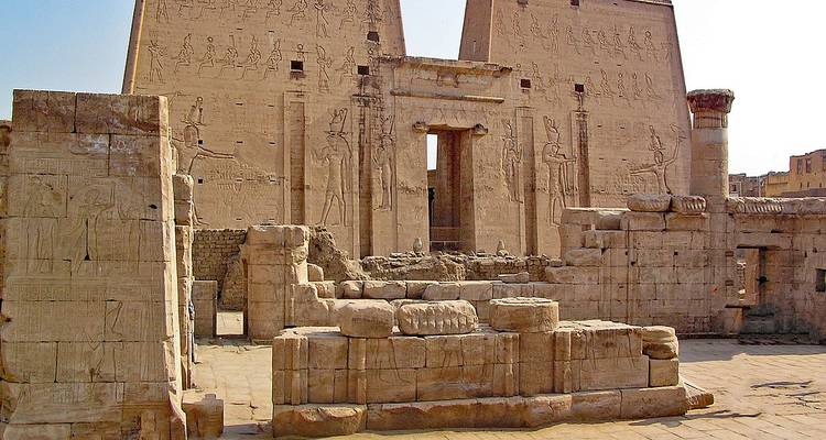 Les murs en grès ancien et les bas-reliefs d'une cour de temple égyptien sous des ciels dégagés.