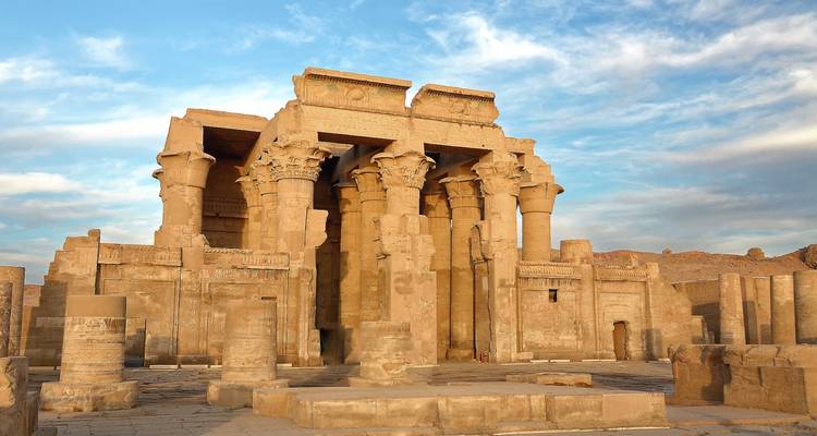 Facade impressionnante du Temple de Kom Ombo brillant dans la lumière douce de l'après-midi contre un ciel bleu.