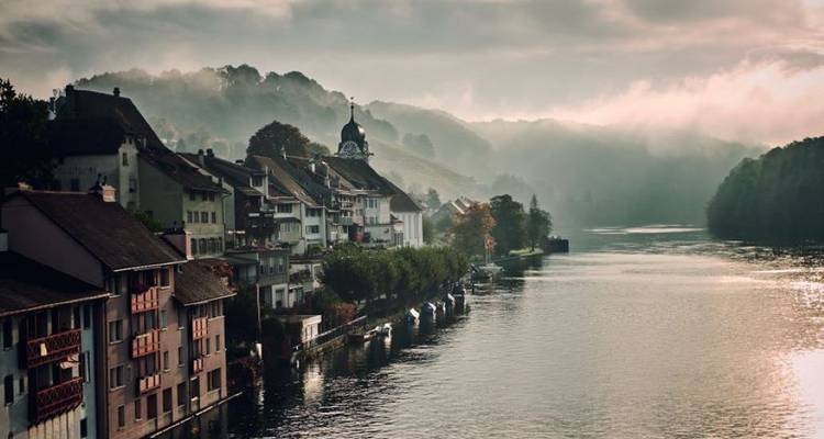 Mistige ochtend over een Duitse stad aan de rivier met kerkkoepel en glooiende heuvels