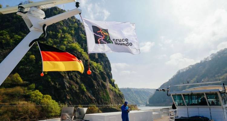 Duitse vlag wappert op een riviercruiseschip dat door een steile rotskloof vaart