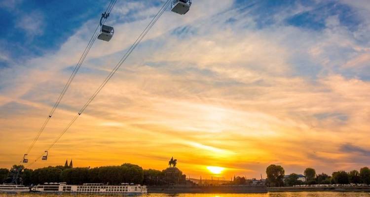 Levendige zonsondergang boven Koblenz met kabelbanen die de Rijn oversteken en gouden hemel