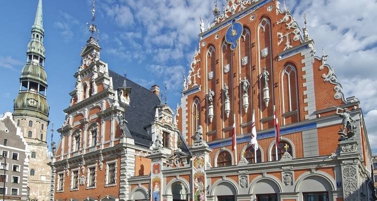 Ornate historical buildings with complex architecture and flags fluttering.