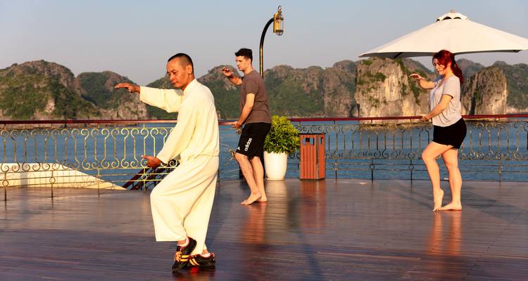 Personas practicando Tai Chi en una terraza con vistas panorámicas.
