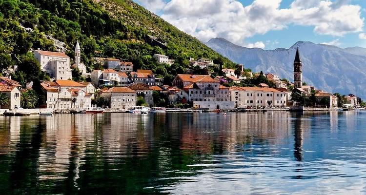 Coastal town with mountains in the background and houses by the sea.