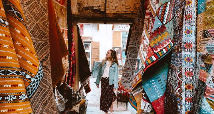 Woman exploring a shop adorned with colorful traditional textiles.