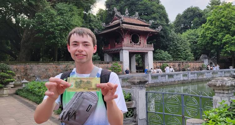 Turista sosteniendo moneda frente al Templo de la Literatura.