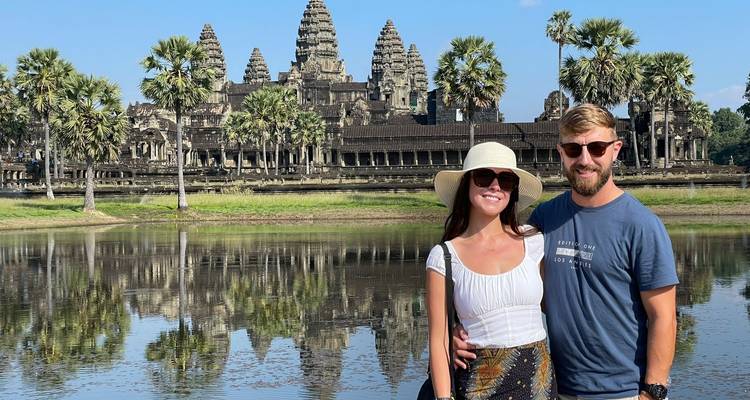 Pareja posando frente a Angkor Wat con agua reflectante.