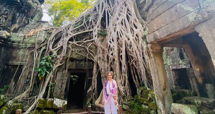 Persona de pie frente a un templo envuelto por raíces de árboles.