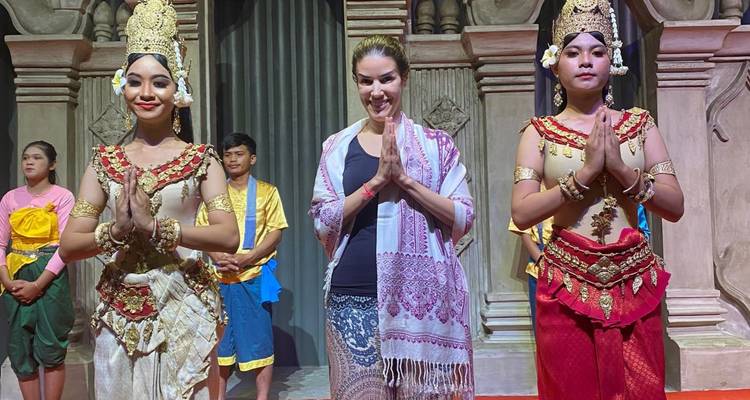 Una mujer de pie en el escenario con bailarines tradicionales.