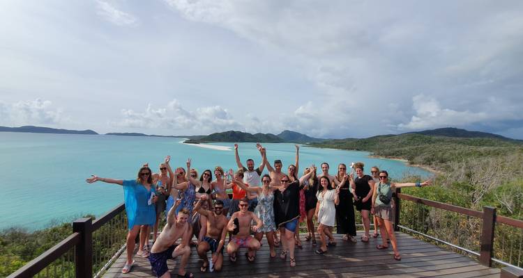 Group of people posing on a scenic overlook with turquoise waters in the background.
