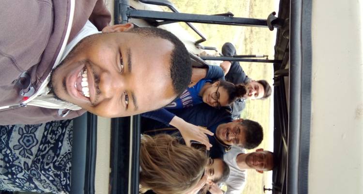 Menschen in einem Touristenfahrzeug, die für ein Gruppen-Selfie lächeln.