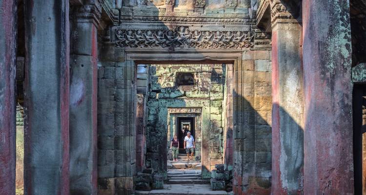 Vue intérieure à travers des ruines de temple antique avec des sculptures en pierre complexes.
