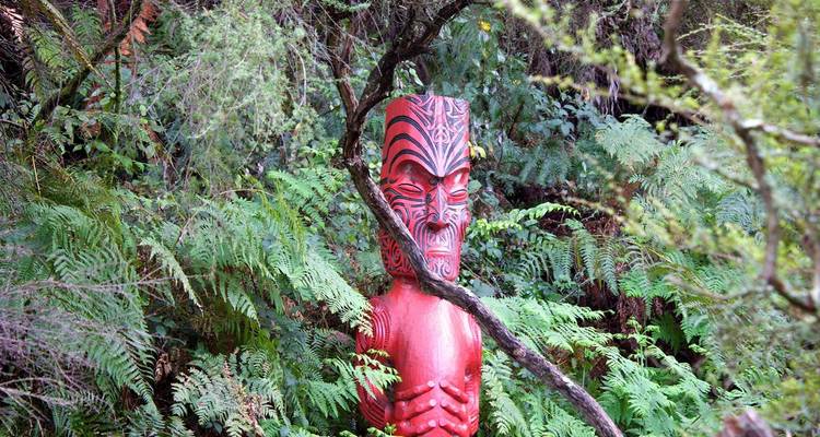 Maori carving surrounded by lush foliage.