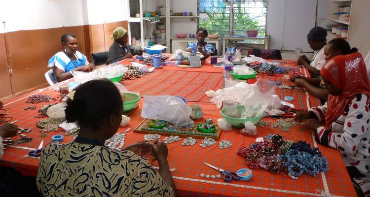 Femmes fabriquant des bijoux autour d'une table.