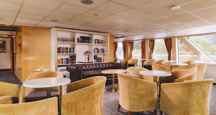 Coin salon avec fauteuils et vue panoramique sur la rivière.