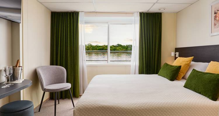Chambre d'hôtel avec vue sur la rivière par la fenêtre.