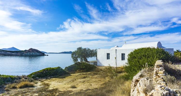 White building by a serene sea with a clear blue sky.