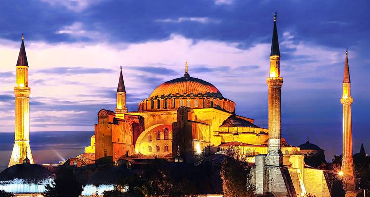 Mosquée illuminée avec des dômes et des minarets proéminents au crépuscule.