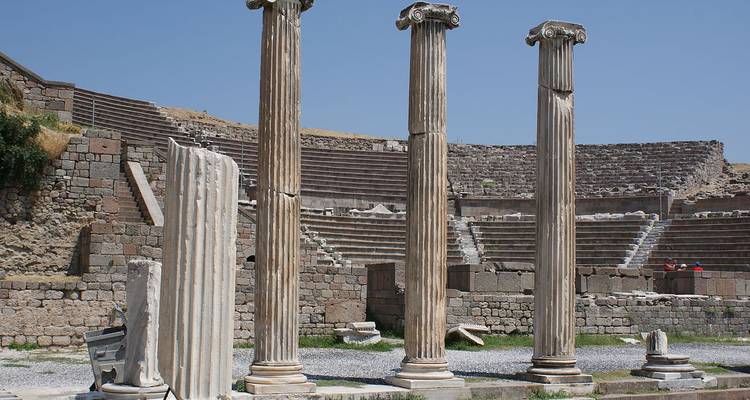Colonnes anciennes disposées dans une structure semi-ruinée sous un ciel bleu clair.