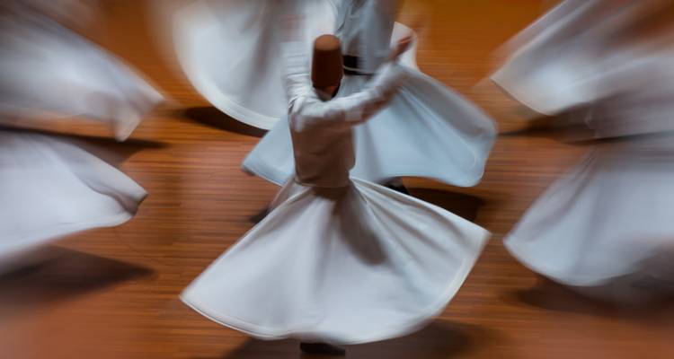 Derviches tourneurs tournoyant dans une performance rythmée avec un flou artistique.