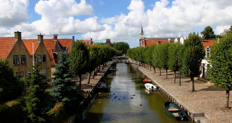 Canal pittoresque bordé d'arbres et de bâtiments traditionnels.