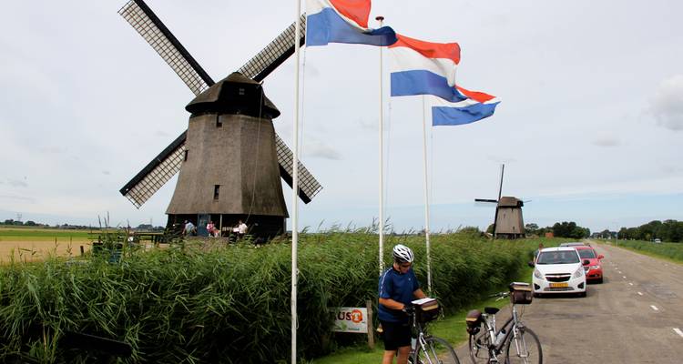 Cycliste à côté d'éoliennes avec drapeau hollandais.