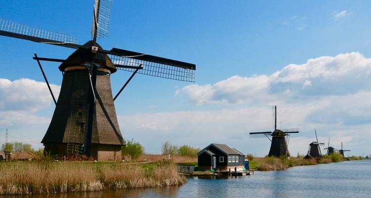Moulins à vent hollandais traditionnels et une maison au bord d'un canal.