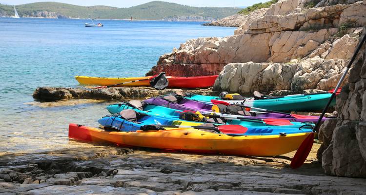 Kayaks coloridos alineados en costas rocosas.