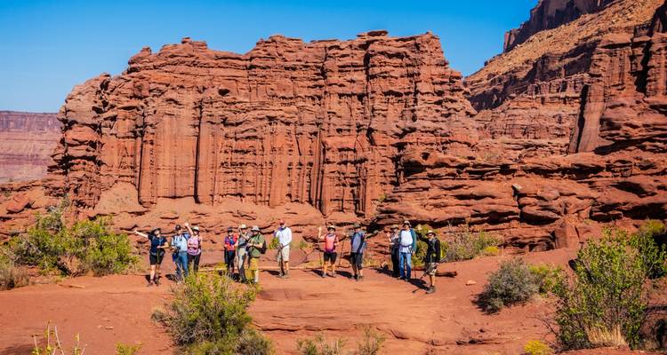 Group of people standing in front of towering red rock formations.