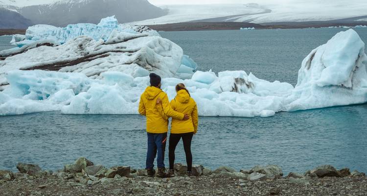 Couple portant des vestes jaunes regardant des icebergs flottants.