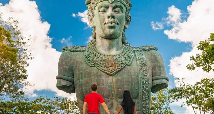 Large statue of a mythical figure with people admiring it.