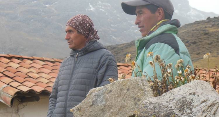 Twee mensen in jassen staan in een bergachtig gebied met pannendaken.