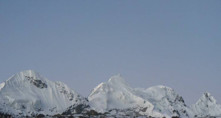 Besneeuwde bergtoppen onder een heldere blauwe hemel bij zonsondergang.