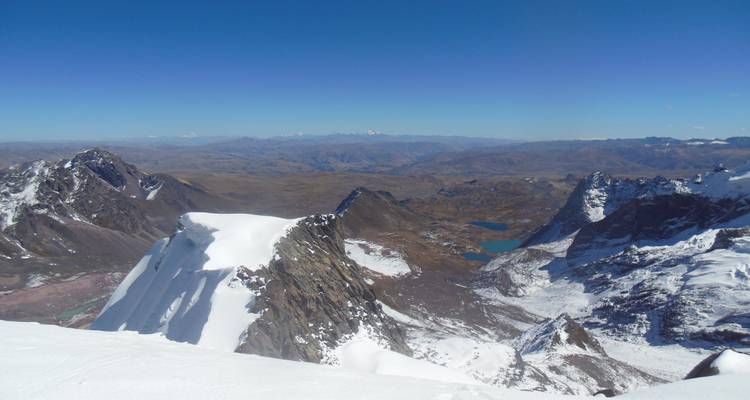 Breed uitzicht op bergen met stukken sneeuw en meren.