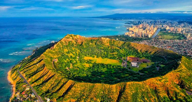 Aerial view of a volcanic crater surrounded by cityscape and ocean in Honolulu.