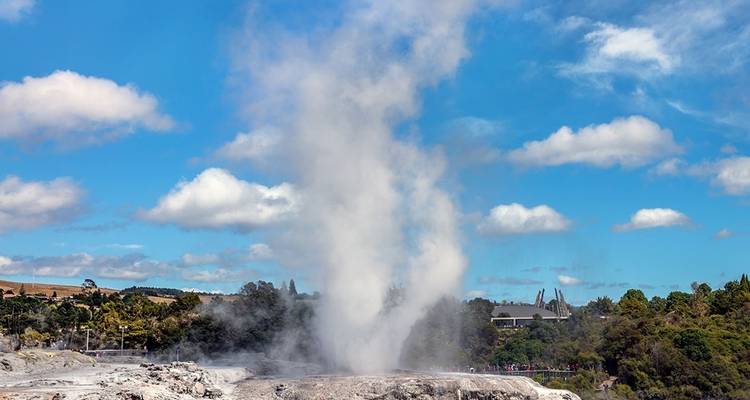 Geyser en éruption avec un ciel bleu en arrière-plan.