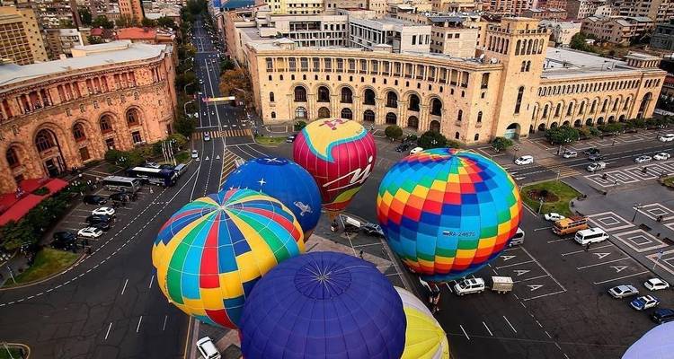 Bunte Heißluftballons, die über einem Stadtplatz aufsteigen
