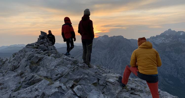 Groupe regardant le coucher de soleil depuis un sommet rocheux de montagne.