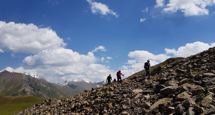 Excursionistas escalando una pendiente rocosa con un telón de fondo montañoso.