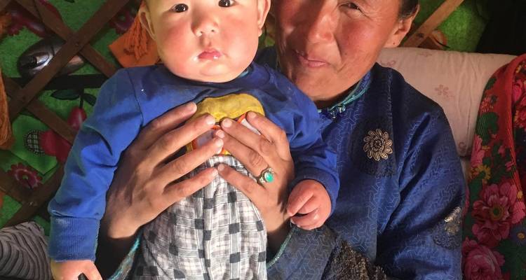 Mujer sosteniendo a un niño dentro de una yurta.