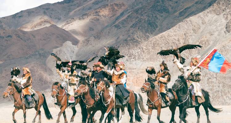 Groupe de personnes à cheval avec des aigles dans un terrain montagneux.