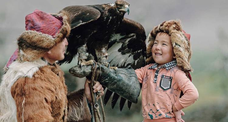 Persona sosteniendo un ave majestuosa con un niño cerca.