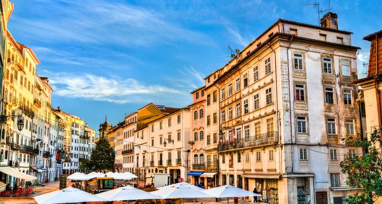 Bâtiments historiques colorés sur une place avec des sièges extérieurs.