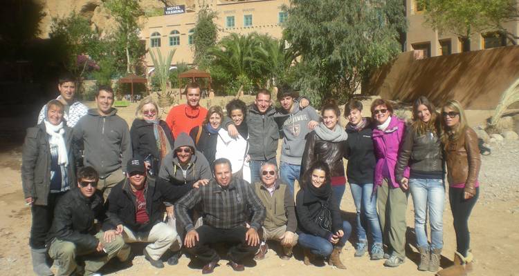 Group photo of people posing together in front of a hotel.
